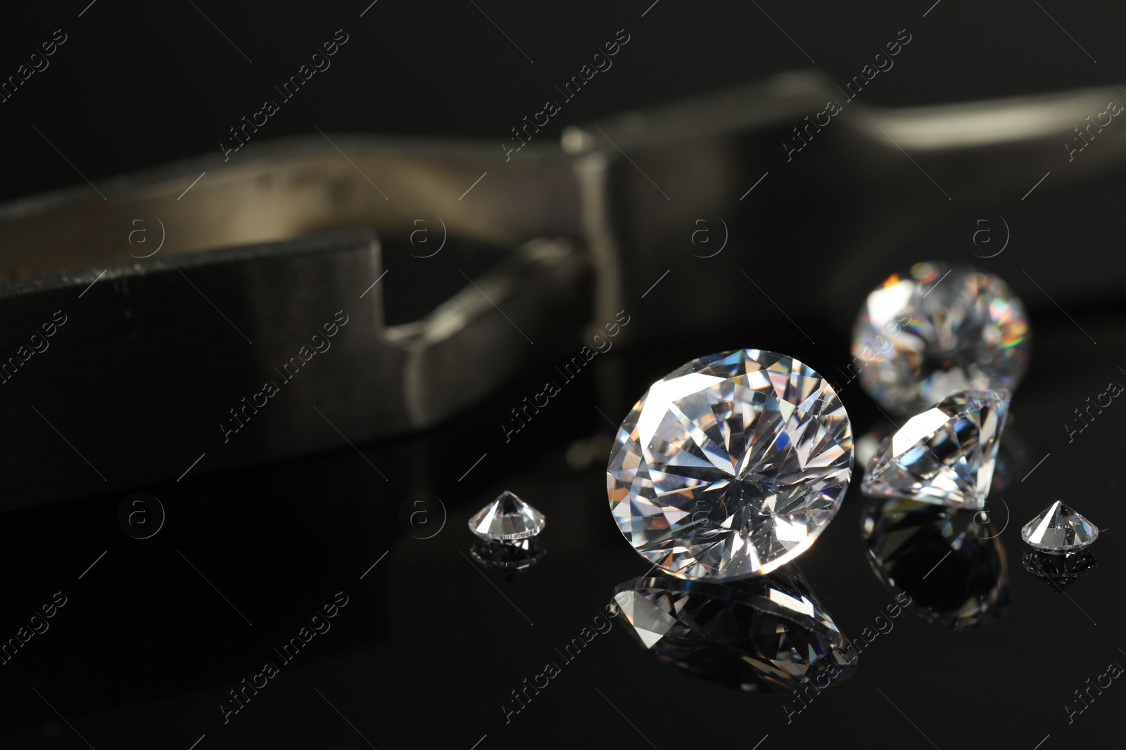 Photo of Many beautiful shiny diamonds on black mirror surface, closeup