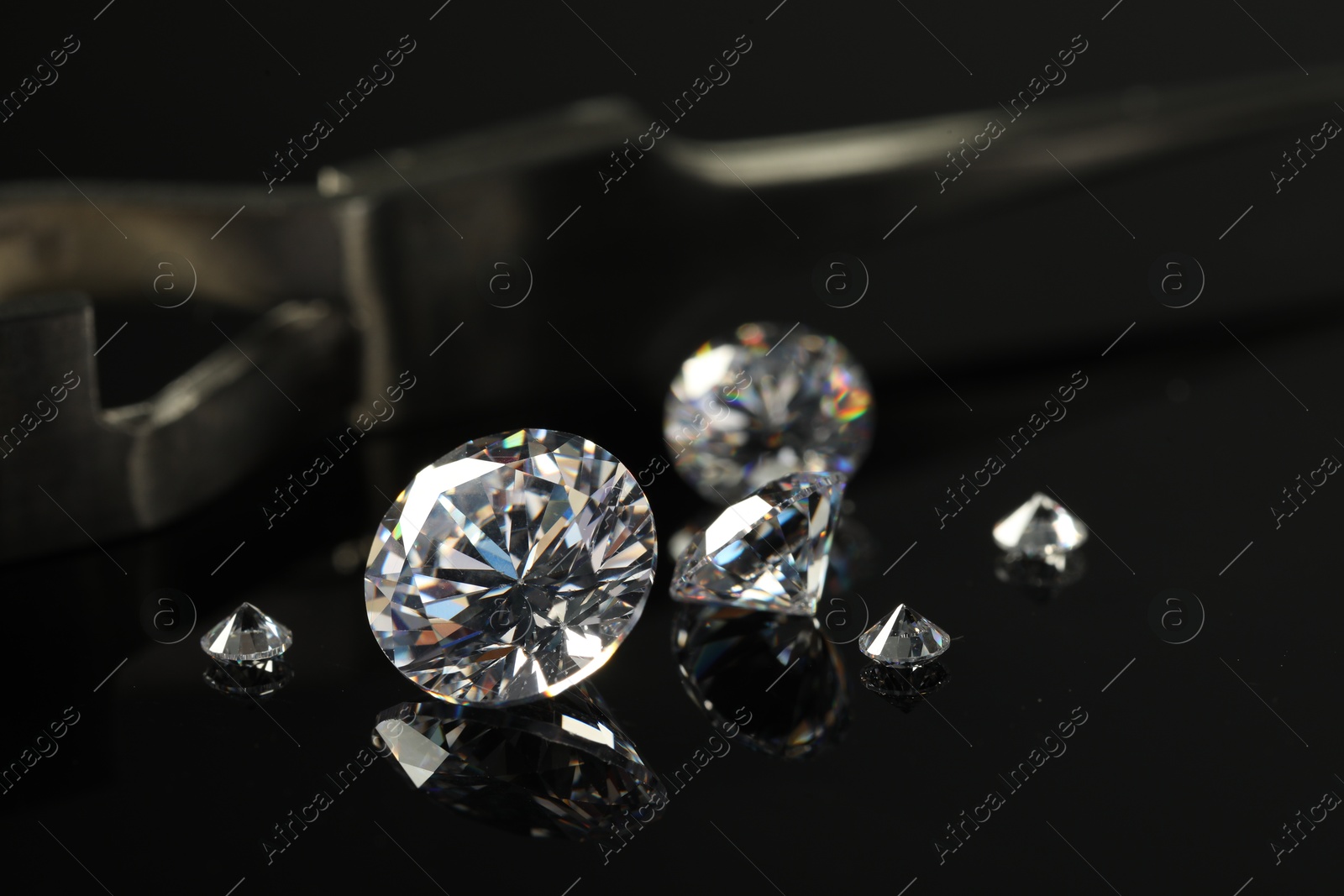 Photo of Many beautiful shiny diamonds on black mirror surface, closeup