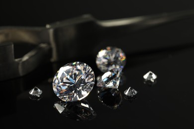 Photo of Many beautiful shiny diamonds on black mirror surface, closeup