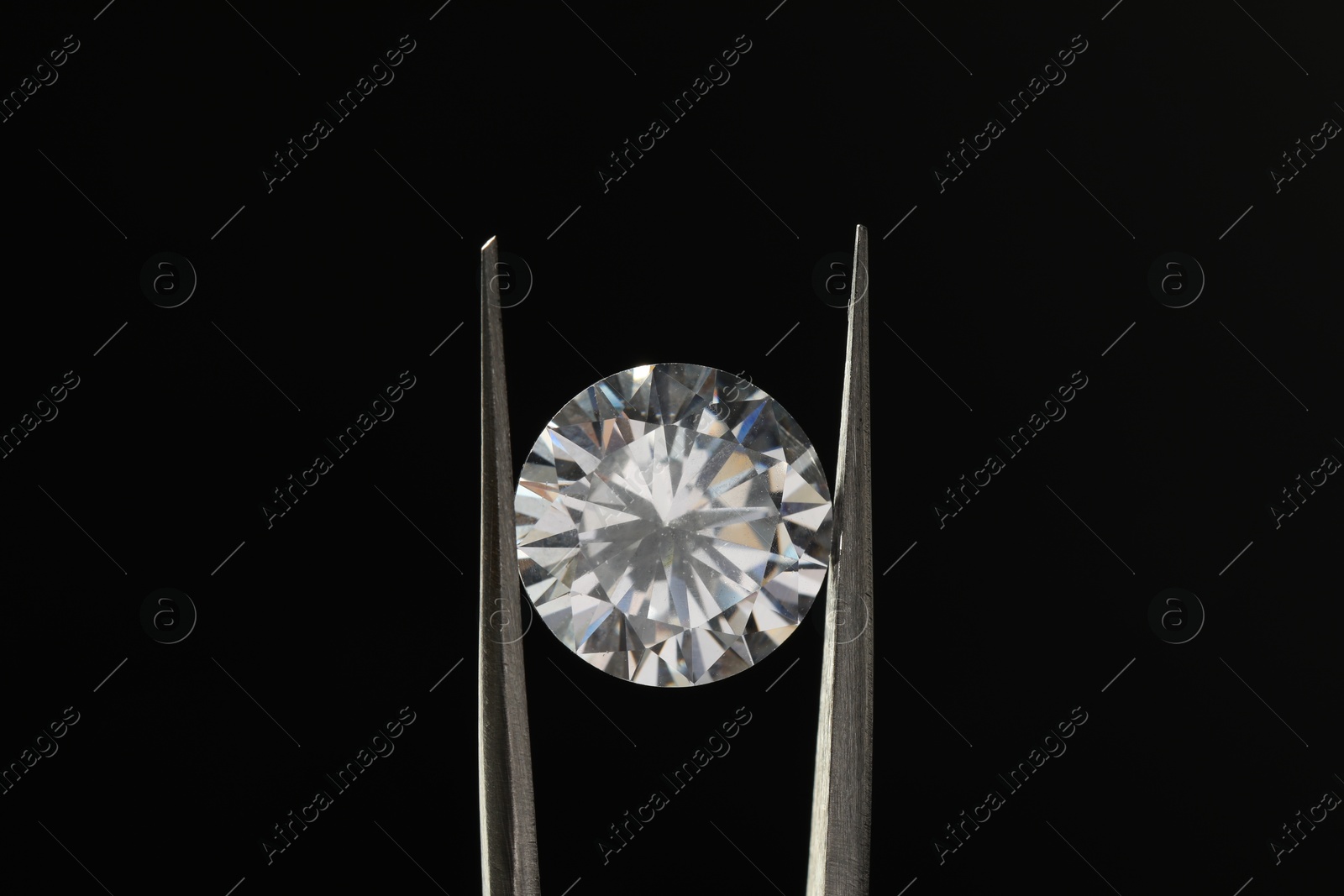 Photo of Tweezers with beautiful shiny diamond on black background, closeup