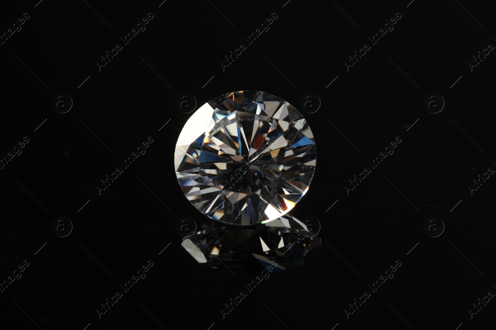 Photo of Beautiful shiny diamond on black mirror surface