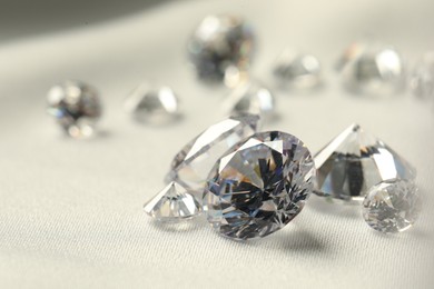 Photo of Many beautiful shiny diamonds on white fabric, closeup