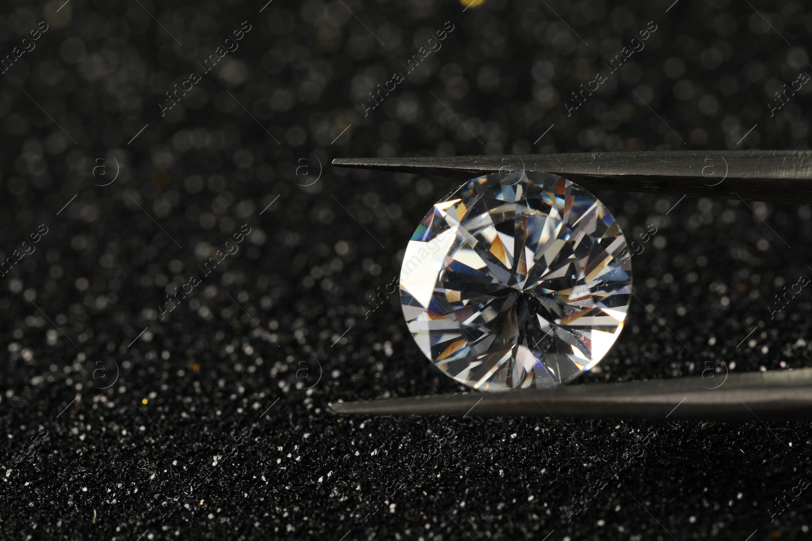 Photo of Tweezers with beautiful diamond on dark shiny background, closeup. Space for text