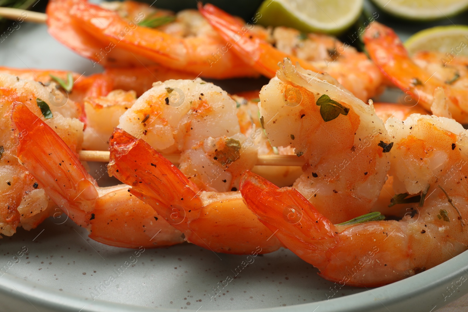 Photo of Skewers with delicious grilled shrimps served on plate, closeup