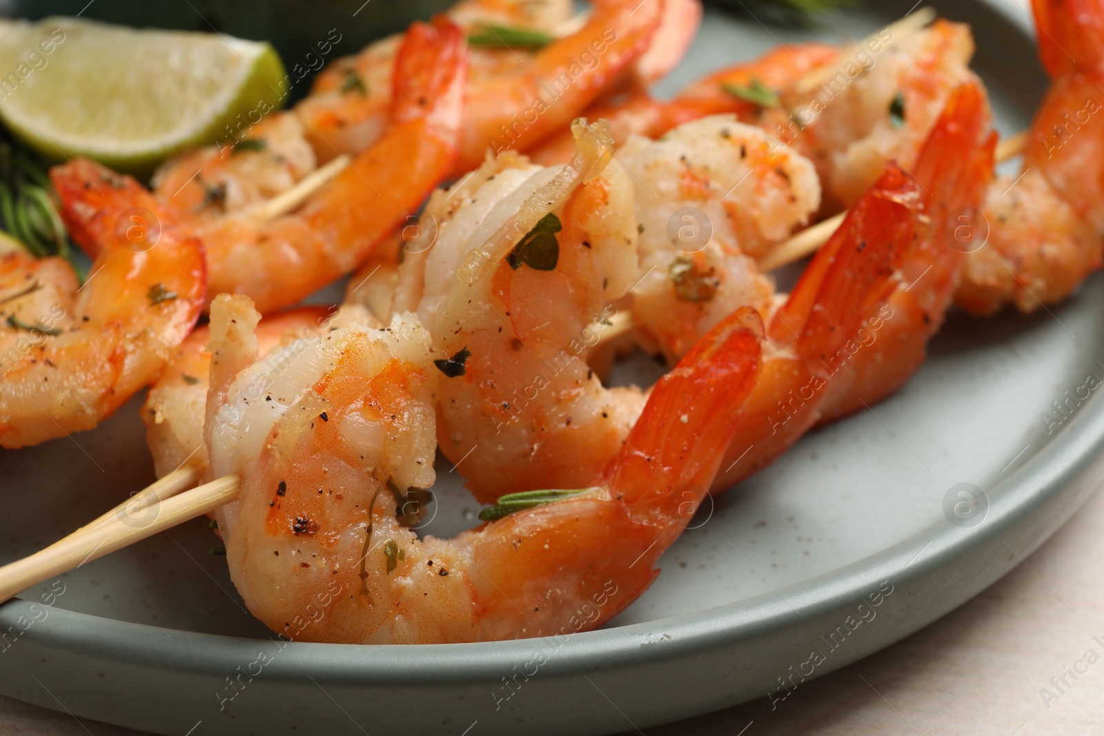 Photo of Skewers with delicious grilled shrimps served on plate, closeup