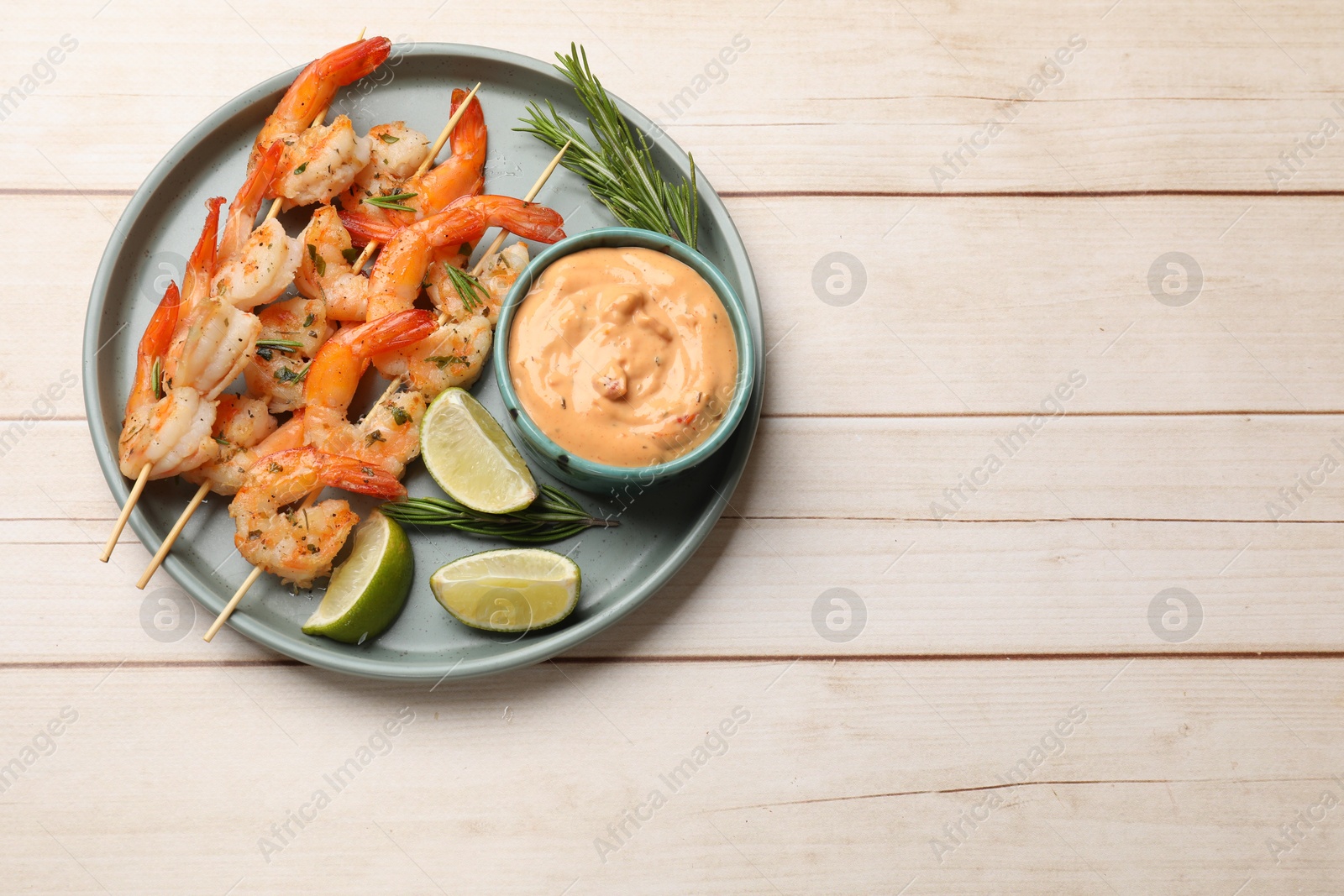 Photo of Skewers with delicious grilled shrimps served on white wooden table, top view. Space for text