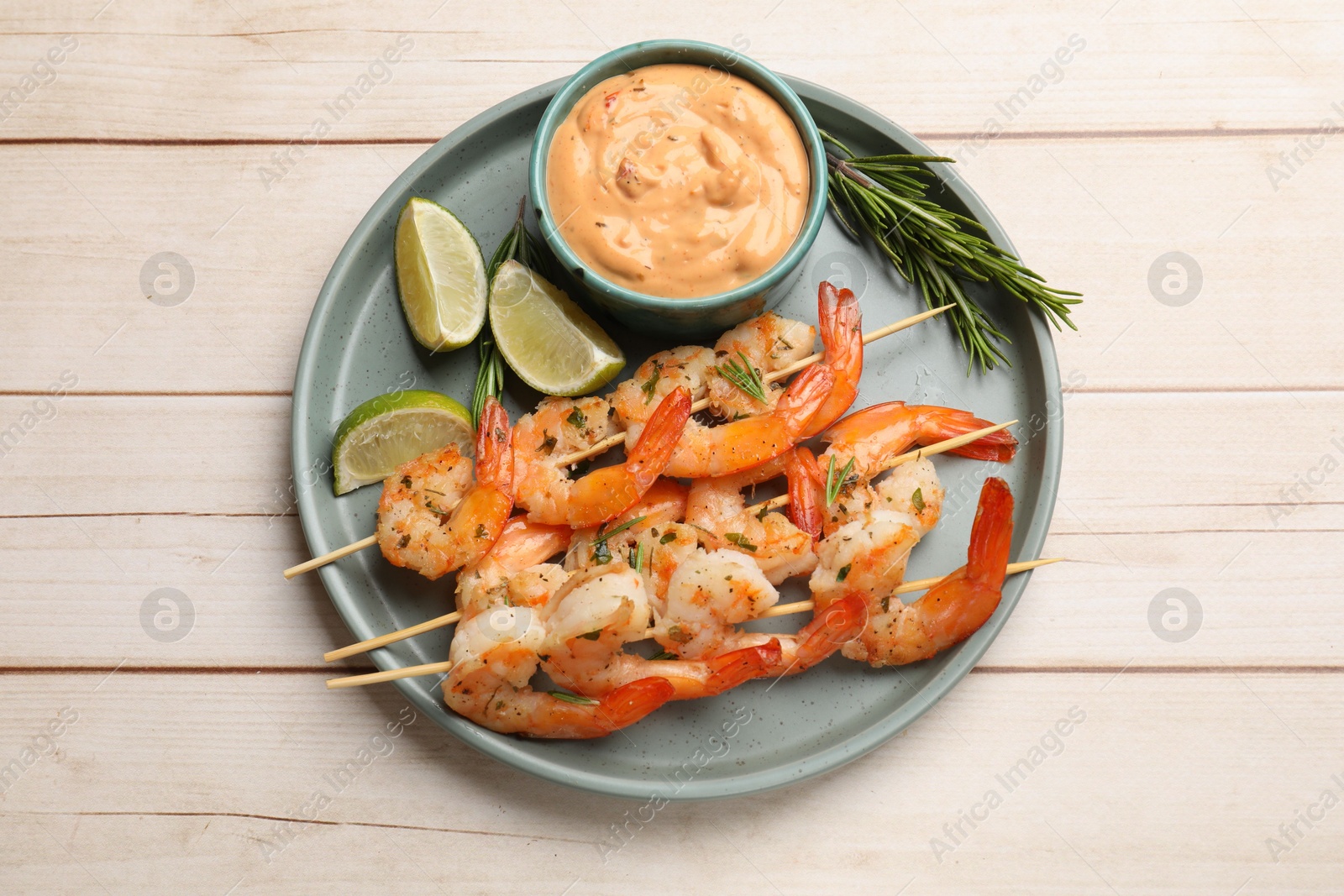 Photo of Skewers with delicious grilled shrimps served on white wooden table, top view