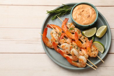 Photo of Skewers with delicious grilled shrimps served on white wooden table, top view. Space for text