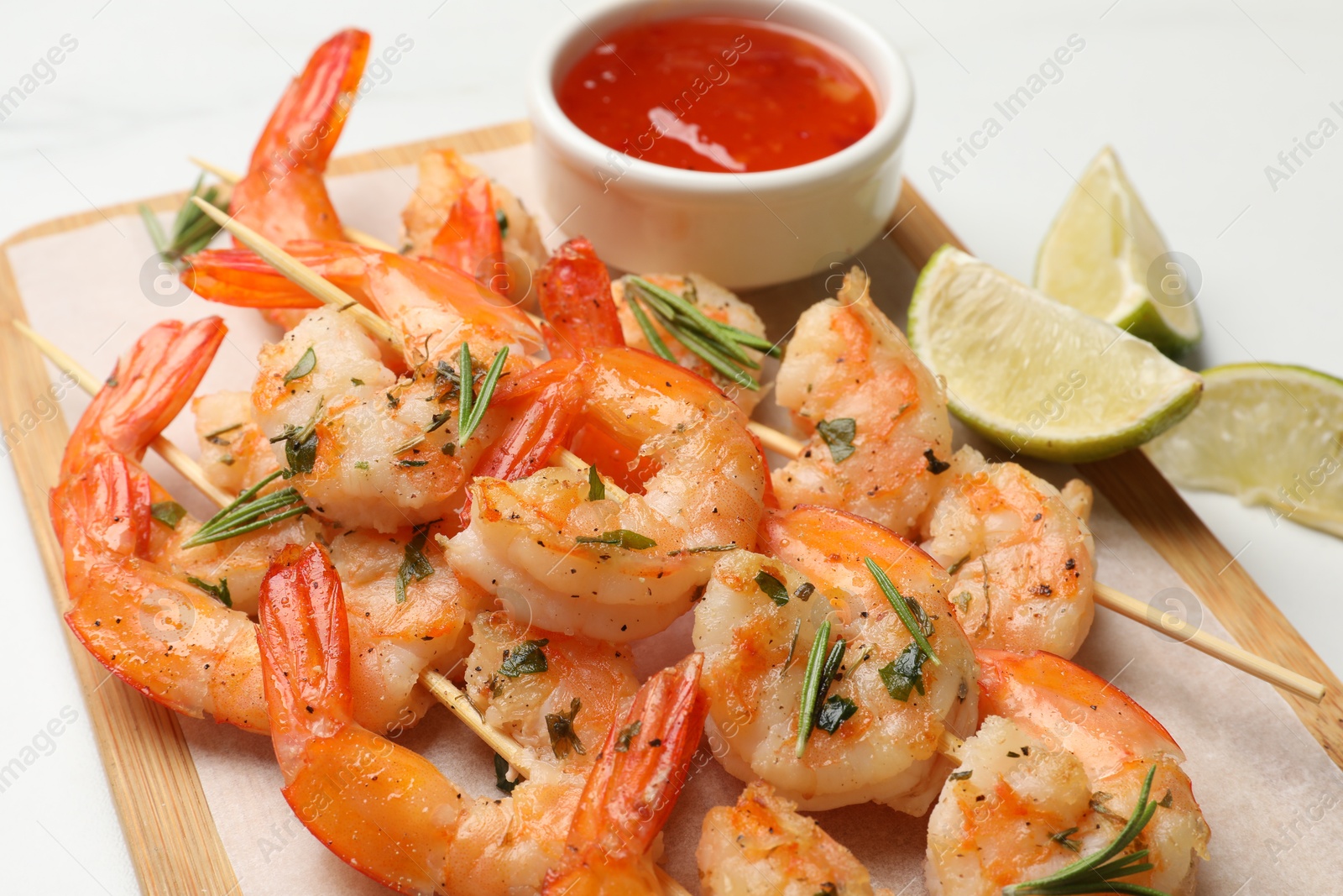 Photo of Skewers with delicious grilled shrimps served on white table, closeup