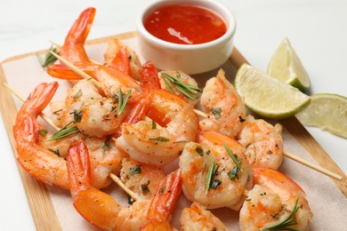 Photo of Skewers with delicious grilled shrimps served on white table, closeup