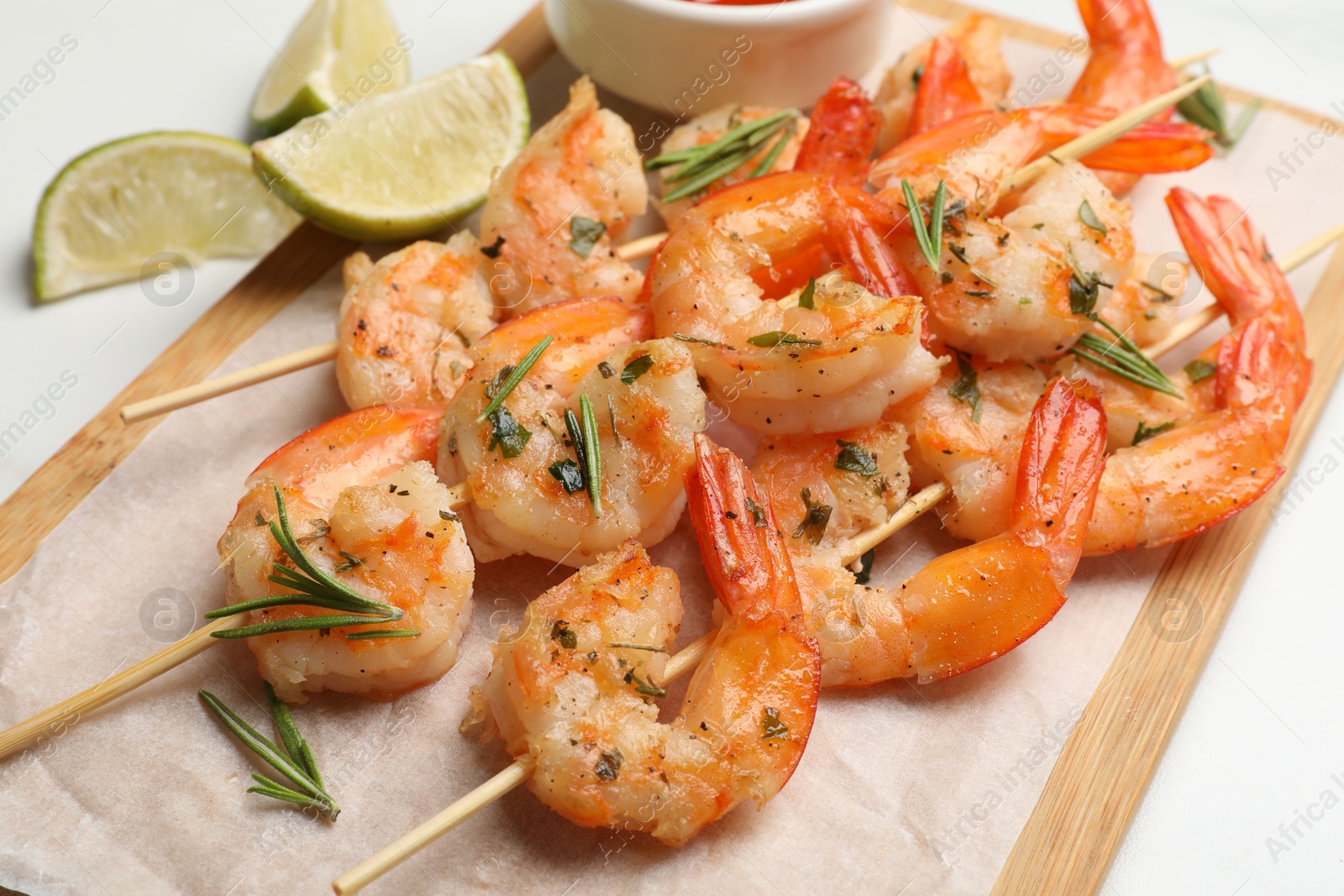 Photo of Skewers with delicious grilled shrimps served on white table, closeup