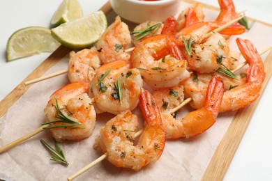 Photo of Skewers with delicious grilled shrimps served on white table, closeup