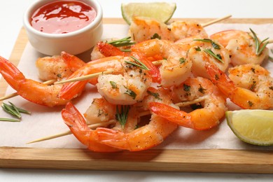 Photo of Skewers with delicious grilled shrimps served on white table, closeup