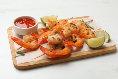 Photo of Skewers with delicious grilled shrimps served on white table