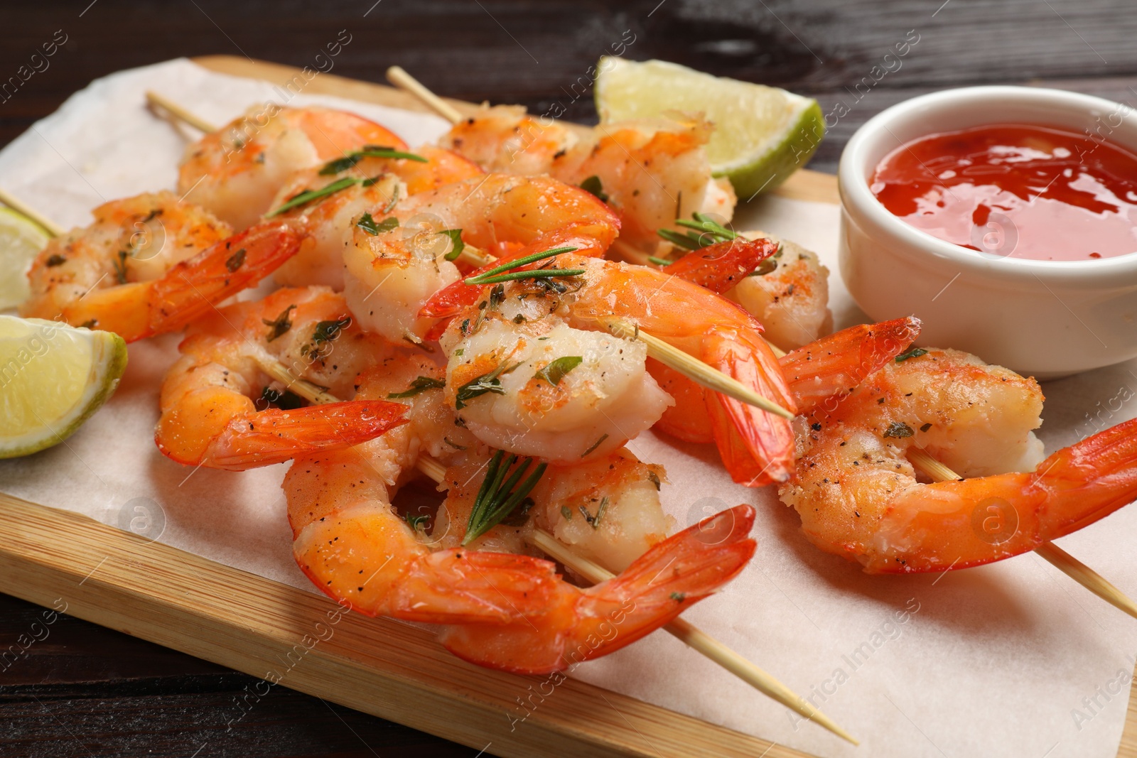 Photo of Skewers with delicious grilled shrimps served on wooden table, closeup