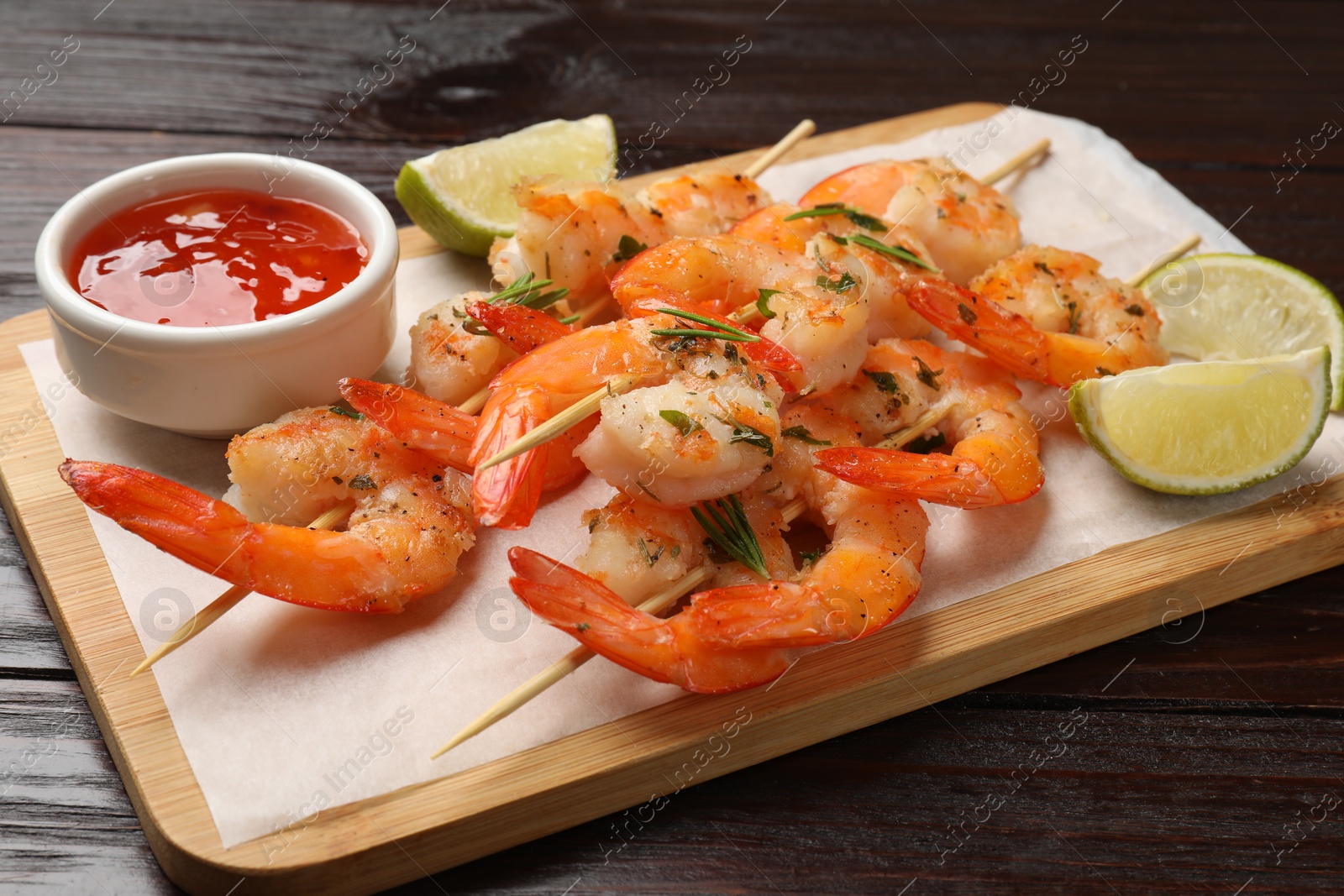 Photo of Skewers with delicious grilled shrimps served on wooden table, closeup