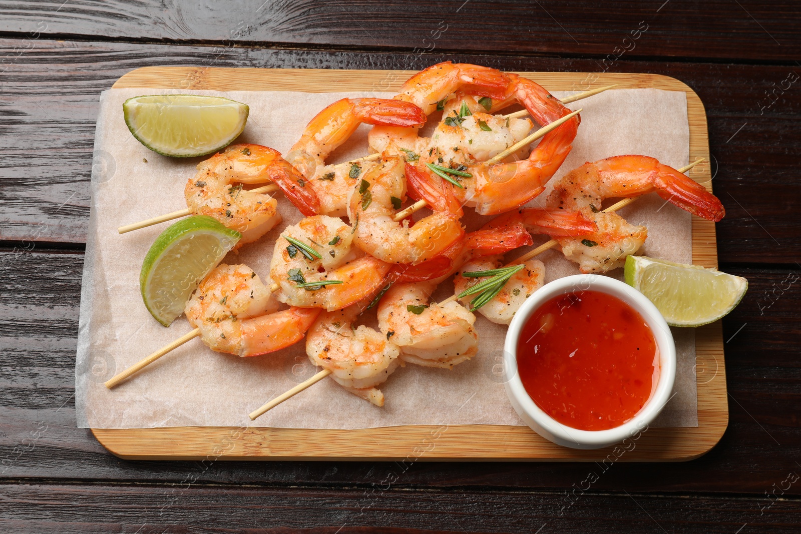 Photo of Skewers with delicious grilled shrimps served on wooden table, top view