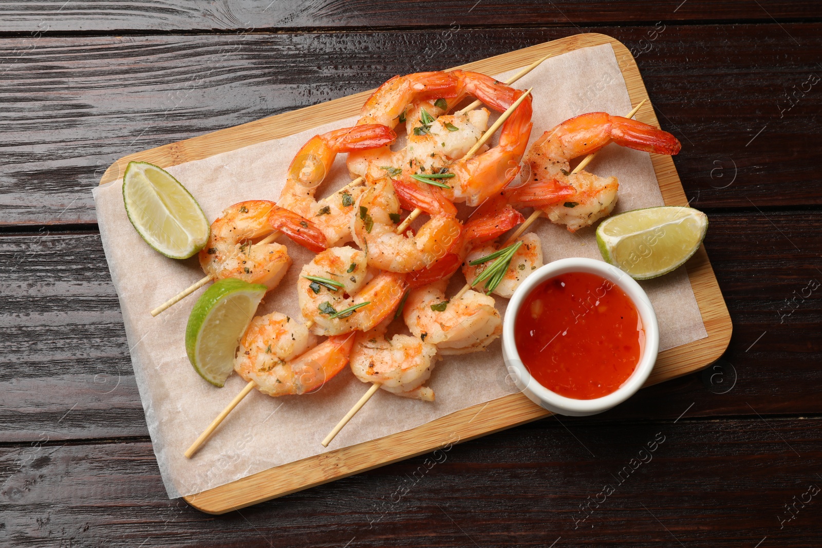 Photo of Skewers with delicious grilled shrimps served on wooden table, top view