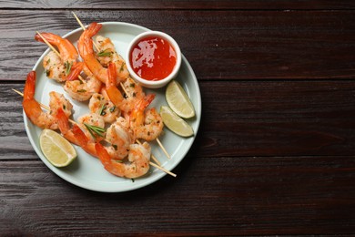 Photo of Skewers with delicious grilled shrimps served on wooden table, top view. Space for text