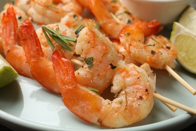 Photo of Skewers with delicious grilled shrimps served on plate, closeup