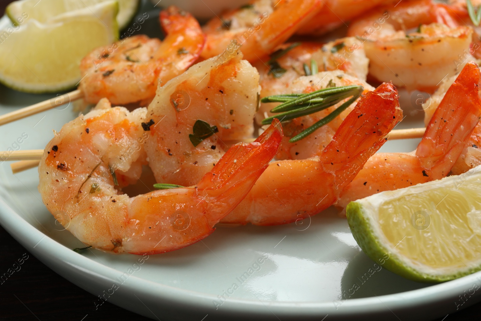 Photo of Skewers with delicious grilled shrimps served on plate, closeup