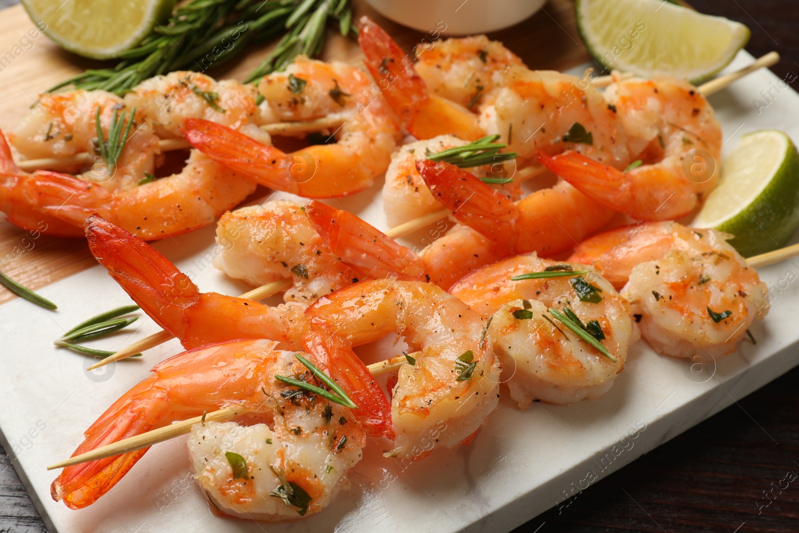 Photo of Skewers with delicious grilled shrimps served on wooden table, closeup