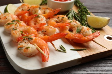 Photo of Skewers with delicious grilled shrimps served on wooden table, closeup