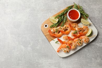 Photo of Skewers with delicious grilled shrimps served on grey table, top view. Space for text