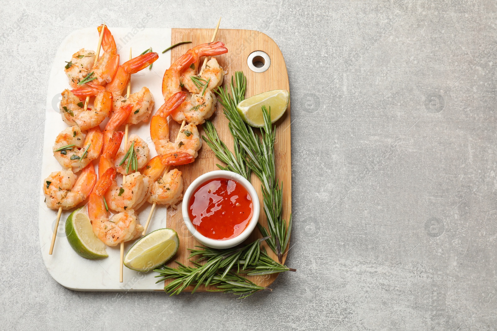 Photo of Skewers with delicious grilled shrimps served on grey table, top view. Space for text