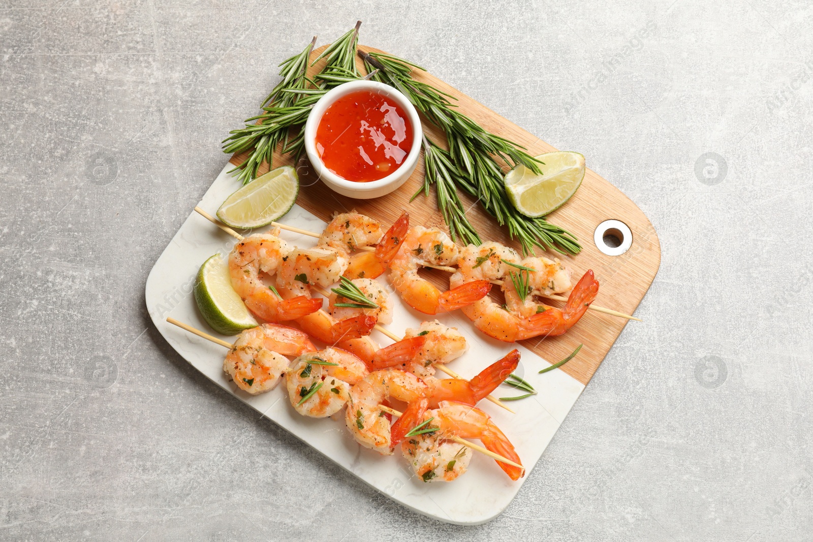 Photo of Skewers with delicious grilled shrimps served on grey table, top view