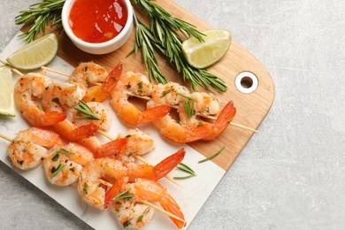 Photo of Skewers with delicious grilled shrimps served on grey table, top view