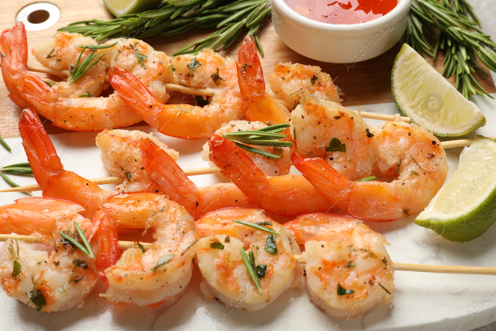 Photo of Skewers with delicious grilled shrimps served on board, closeup