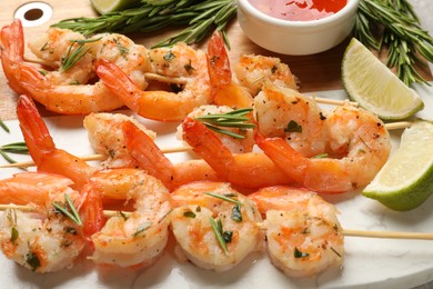 Photo of Skewers with delicious grilled shrimps served on board, closeup