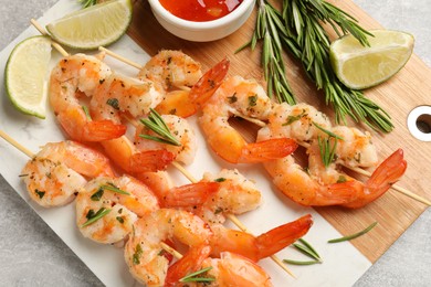 Photo of Skewers with delicious grilled shrimps served on grey table, closeup