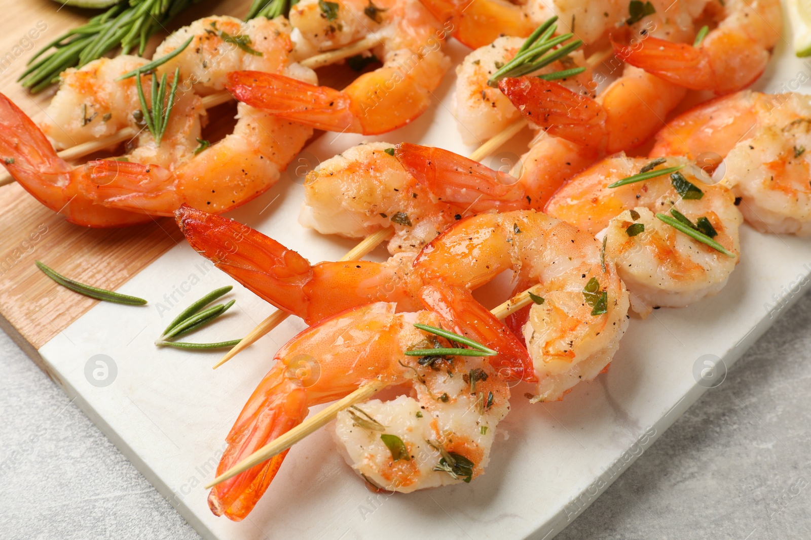 Photo of Skewers with delicious grilled shrimps served on grey table, closeup