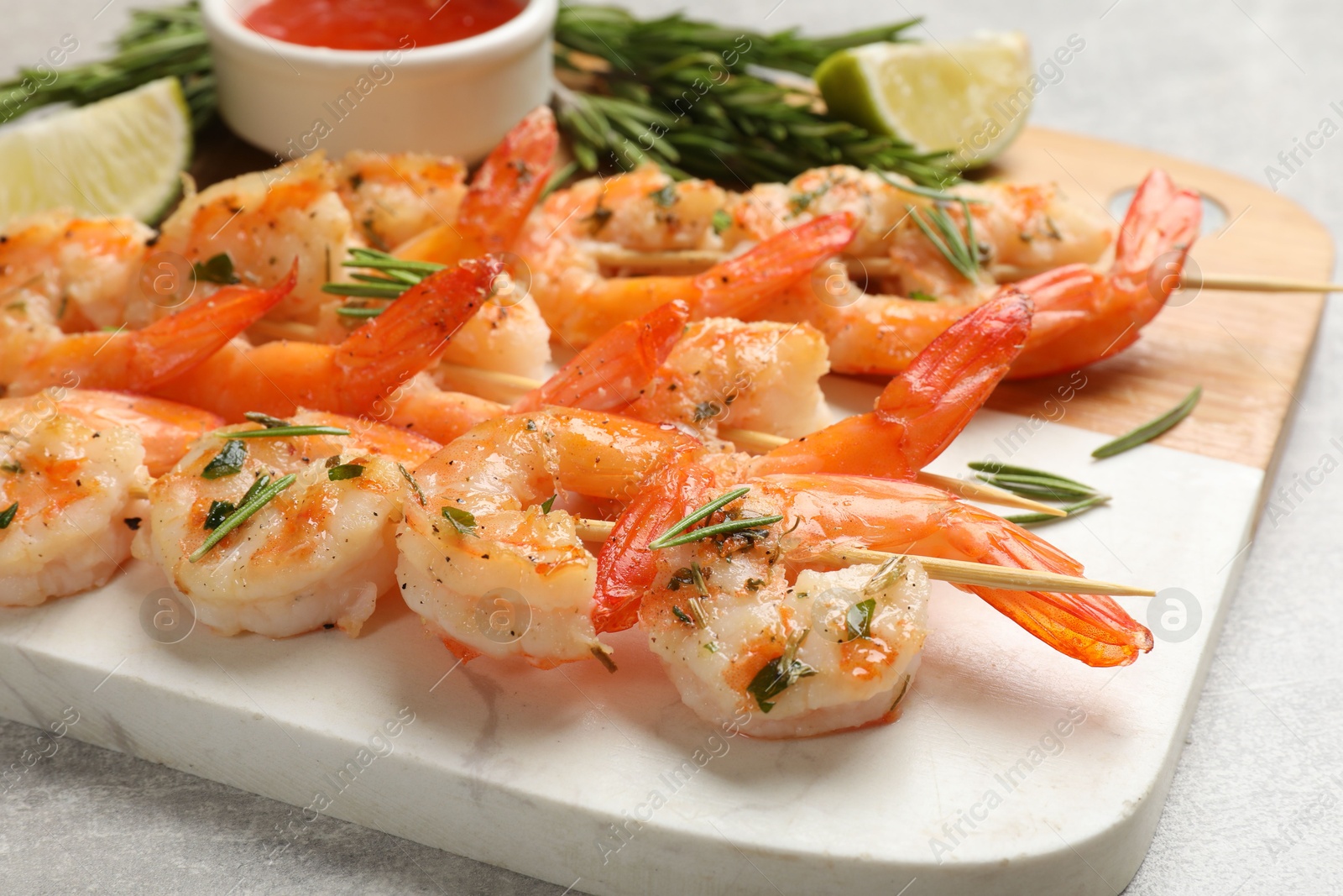 Photo of Skewers with delicious grilled shrimps served on grey table, closeup