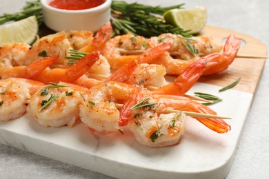 Photo of Skewers with delicious grilled shrimps served on grey table, closeup