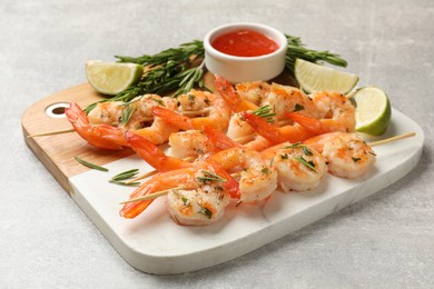 Photo of Skewers with delicious grilled shrimps served on grey table