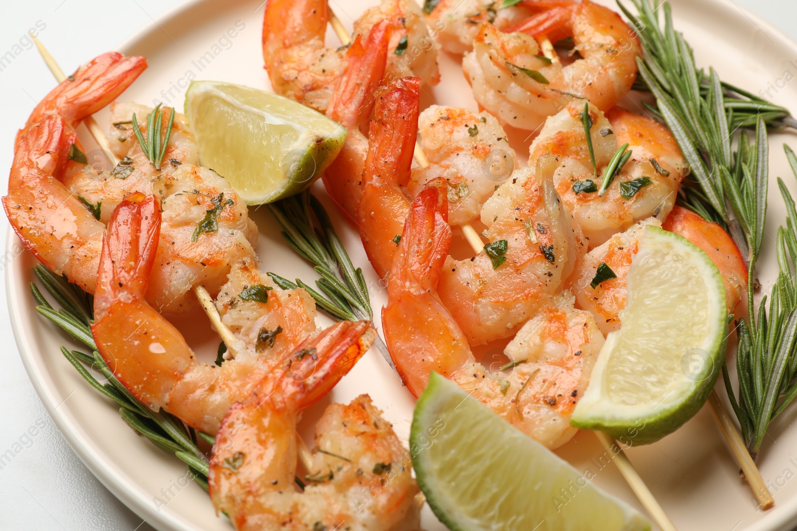 Photo of Skewers with delicious grilled shrimps served on plate, closeup