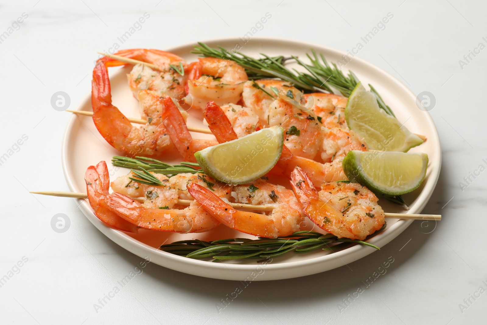 Photo of Skewers with delicious grilled shrimps served on white table