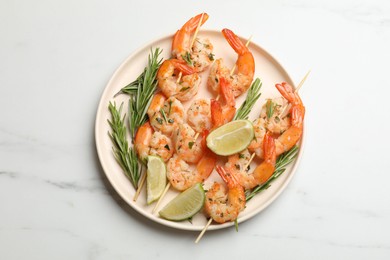 Photo of Skewers with delicious grilled shrimps served on white table, top view