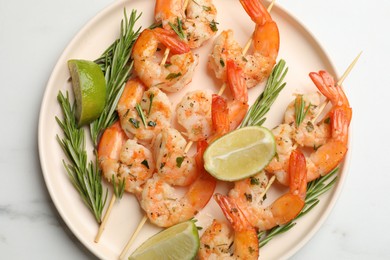 Photo of Skewers with delicious grilled shrimps served on white table, top view