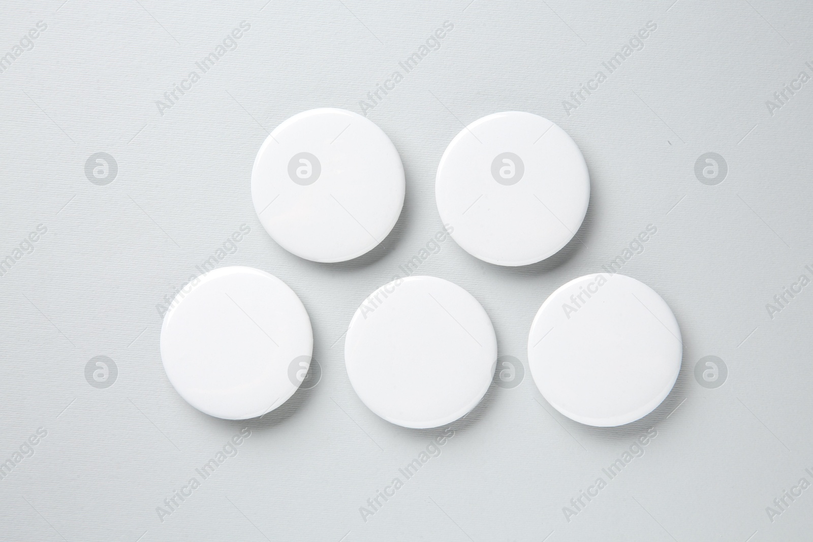 Photo of Blank white button badges on light background, flat lay. Mockup for design