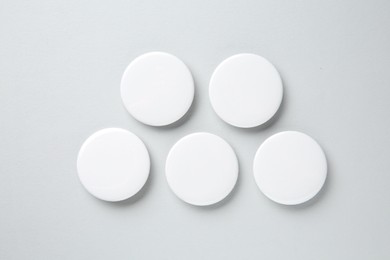 Photo of Blank white button badges on light background, flat lay. Mockup for design