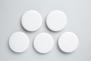 Blank white button badges on light background, flat lay. Mockup for design