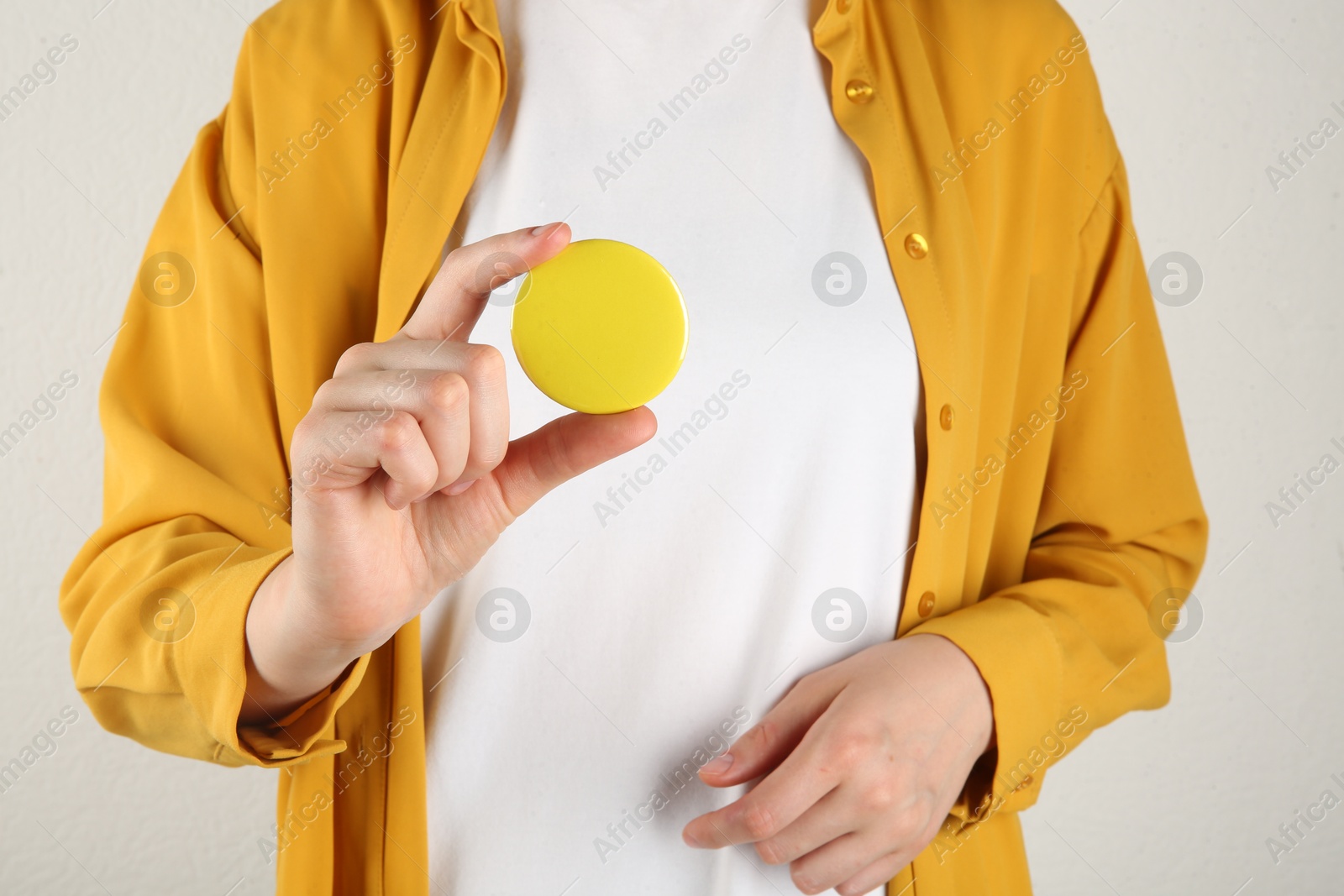 Photo of Woman with blank yellow button badge on light background, closeup