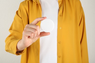 Photo of Woman with blank white button badge on light background, closeup