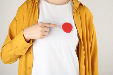 Photo of Woman with blank red button badge on light background, closeup