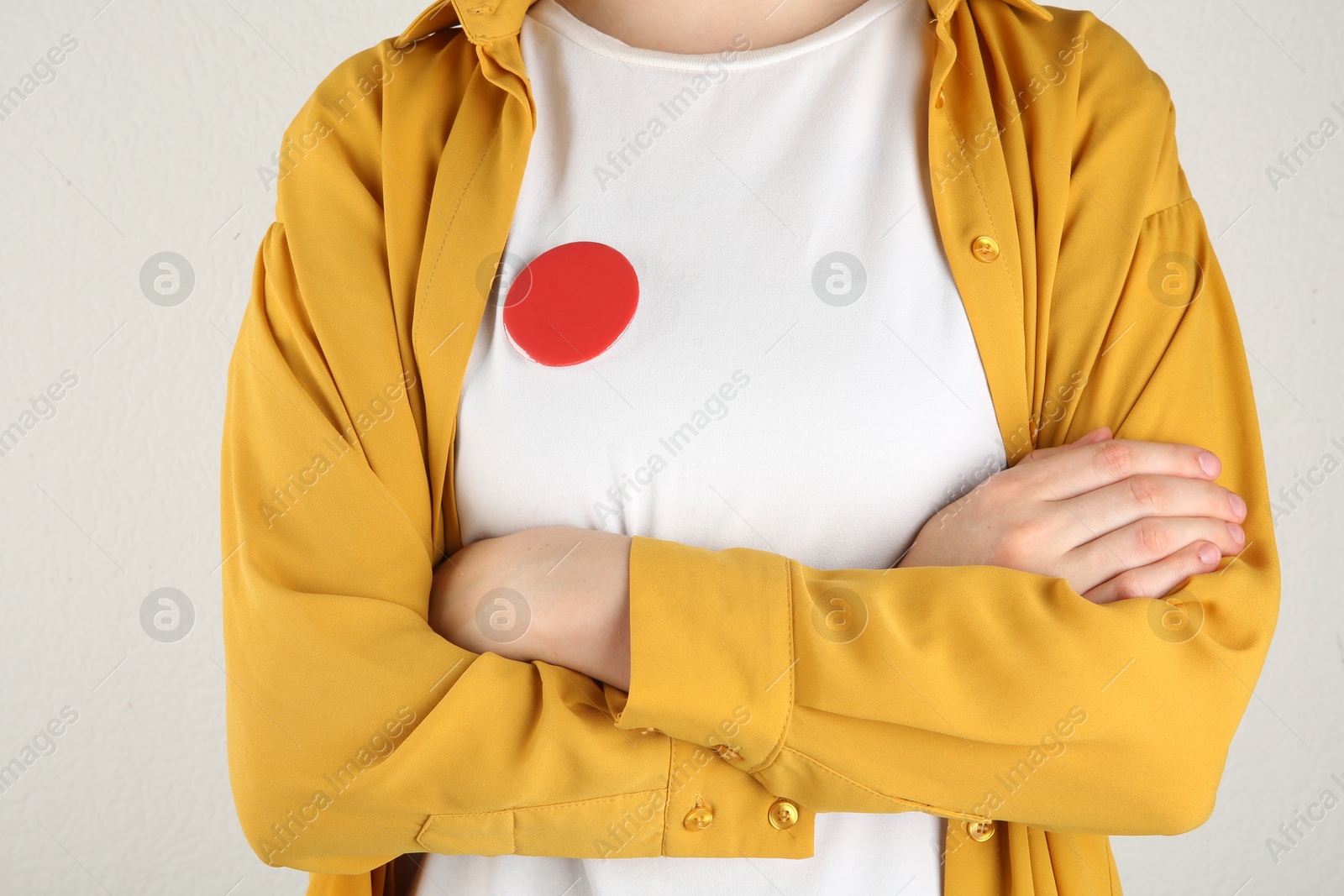 Photo of Woman with blank red button badge on light background, closeup