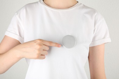 Photo of Woman with blank grey button badge on light background, closeup